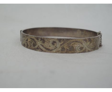 An HM silver hinged bangle having engraved scroll decoration