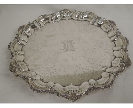 An Edwardian silver salver having moulded scroll decoration to pie crust rim, engraved decoration and engraved inscription an