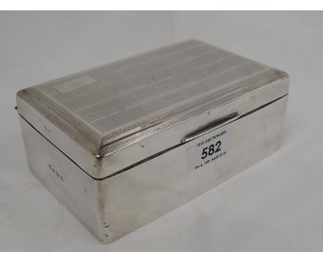 A silver cigarette box of rectangular form having engine turned stripe decoration and plain cartouche to lid, Birmingham 1928