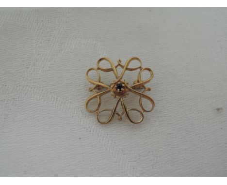 A 9ct gold brooch having a small central sapphire within an open twist decorative surround