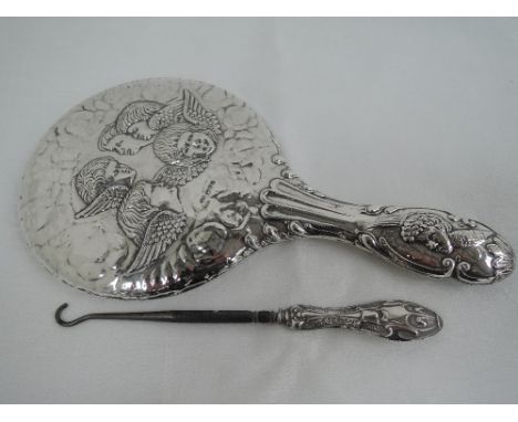A silver hand mirror having moulded cherub decoration, Chester 1911, J & R Griffin, and an HM silver handled button hook