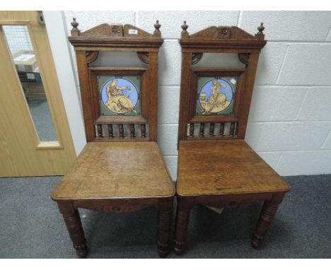 A pair of late Victorian oak hall chairs having spindle and Minton tile inset backs by Moyr Smith, with solid seats and turne