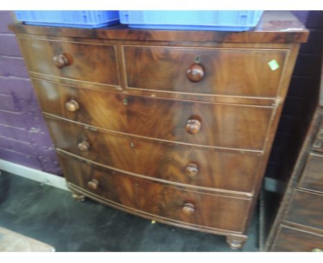 An early 19th century mahogany bow front chest of 2 short and 3 long cockbeaded drawers on later turned feet