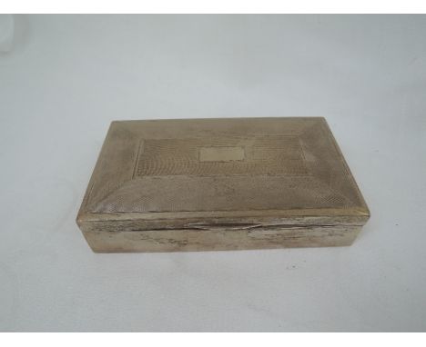 A silver cigarette box of shallow rectangular form having engine turned decoration and plain cartouche, Birmingham 1963, Harm