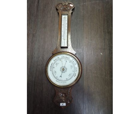An Edwardian oak frame aneroid banjo barometer having carved decoration with thermometer scale and circular dial