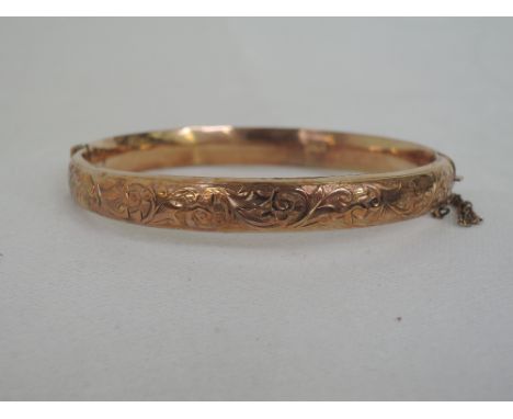 A 9ct rose gold hinged bangle having engraved scroll decoration, approx 8.7g