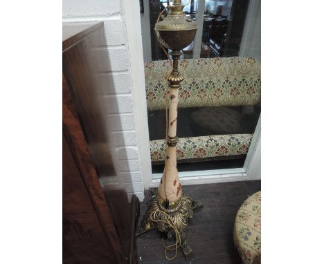 A Victorian brass and ceramic oil lamp base converted to standard lamp having embossed brass reservoir with floral column and