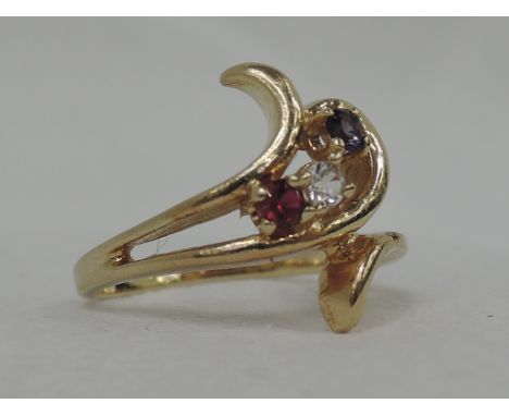 A lady's dress ring having three non precious stones in a stylised setting on a yellow metal loop stamped 14K,  size K