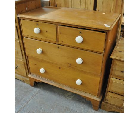 Victorian pine straight front chest of two short and two long drawers with white ceramic turned handles on a projecting base 
