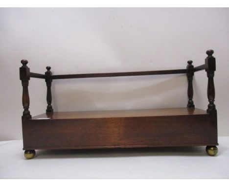 A Regency mahogany book trough with turned spindle columns and rectangular rails over an end drawer, on brass ball feet, 10 1