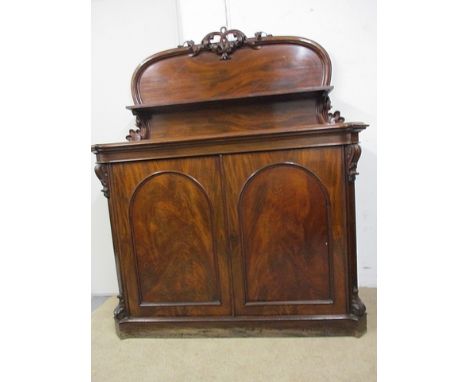 A mid Victorian mahogany chiffoniere, the up-stand having a carved crest over a shelf, the base comprising canted flanks and 