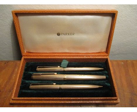 A 9ct gold cased, three piece Parker pen set with engine turned decoration, to include a fountain pen, a ball point pen and a