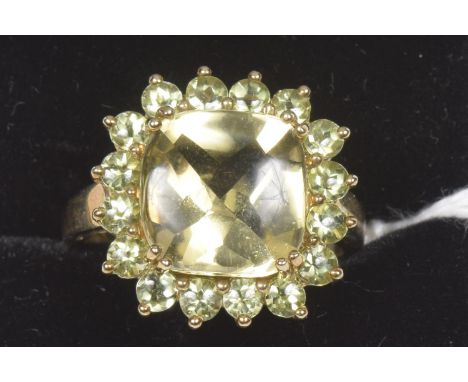 A 9ct gold peridot cluster ring The square shape peridot within a circular shape peridot cluster surround, hallmarks for Birm