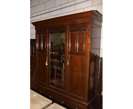 An early 20th century mahogany wardrobe, Having a cavetto cornice above a central mirrored door flanked by two paneled doors 