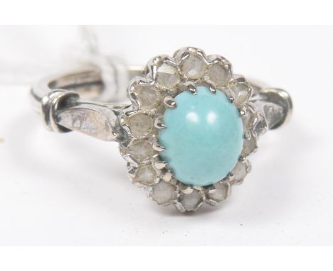 A turquoise and diamond cluster ringThe oval turquoise cabochon within a rose cut diamond surround, ring size L1/2, weight ap