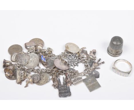 A silver charm braceletThe flat curb link chain suspending various charms with a silver thimble and a ring, total weight appr