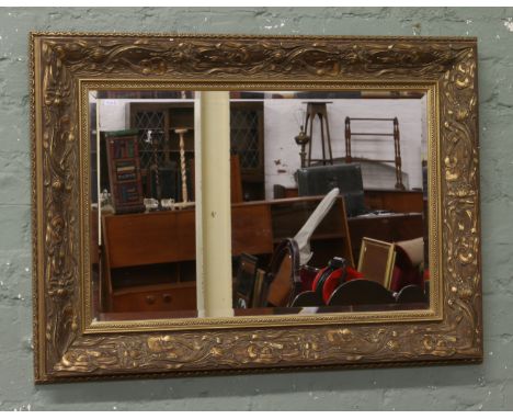 A gilt framed decorated bevel edge wall mirror.