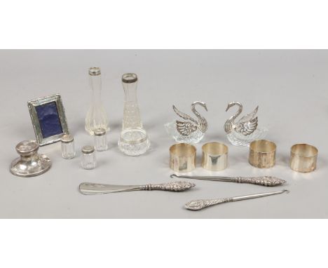 A box of silver, white metal and glass items including a silver captains inkwell, photograph frame and a pair of swan formed 