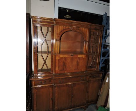 A George III style yew breakfront cabinet, the upper section with a central arched recess flanked by astragal doors, the base