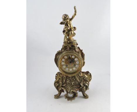 A 20th century cast brass rococo style mantle clock, with a cherub surmount, the dial set out with Roman numerals, H. 41cm