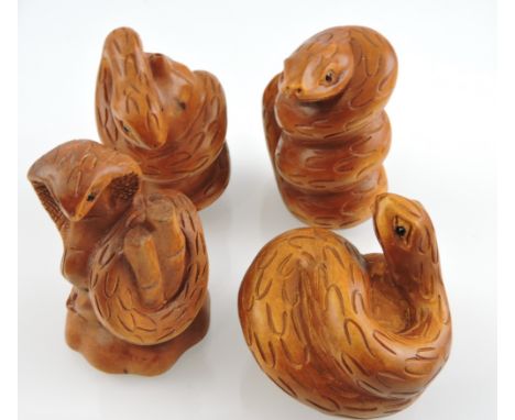A carved hardwood netsuke of a snake, wrapped around a gourd, together with three similar.