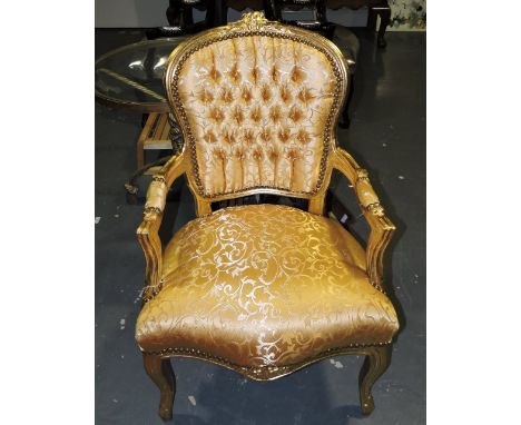 A carved giltwood fauteuil, with button upholstered back, and covered a gold damask fabric.