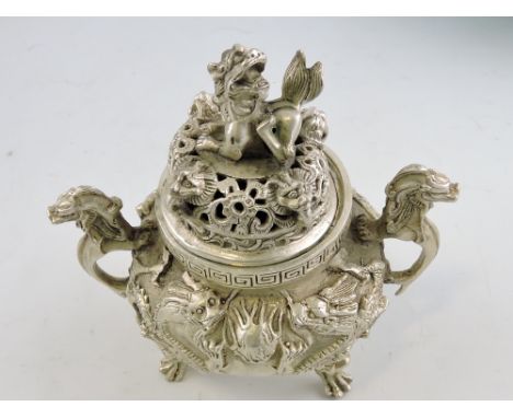 A white metal cast incense burner, cast with dragons chasing a flaming pearl, raised on mask and claw feet, H. 17cm.