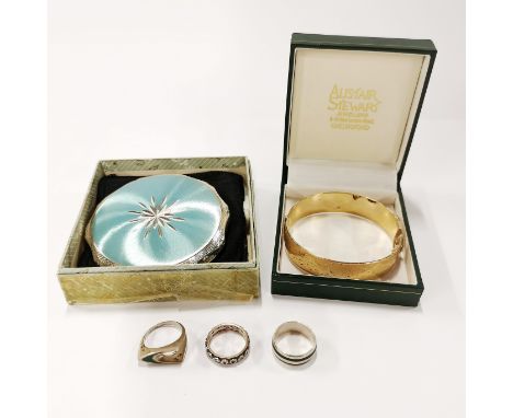 A 9ct gold metal core bangle together with three silver rings and a powder compact.