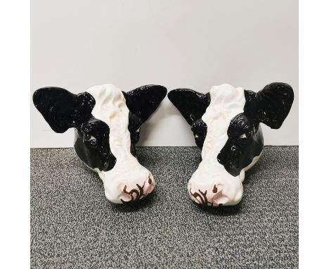 A pair of ceramic cow head wall plaques, W. 25cm, wall to nose 20cm.
