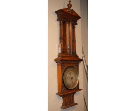 Early 20th Century heavily carved oak aneroid barometer and thermometer, the thermometer flanked by turned and reeded pillars