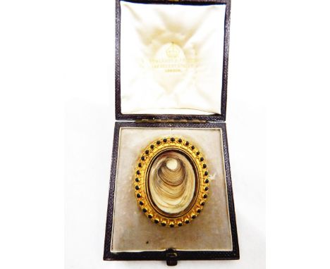 Victorian gold-coloured metal mourning brooch, oval with black enamel jewelled and filigree border, woven head to the centre 