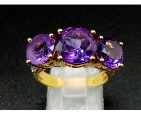 An 18K Yellow Gold and Large Three-Stone Amethyst and Diamond Ring. Three central intense clean amethysts with diamond cluste