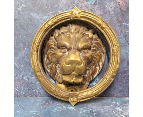 A large brass lion mask door knocker, &nbsp;the mask within a reeded ring knocker cast with floral bosses and sprigs, 21cm di