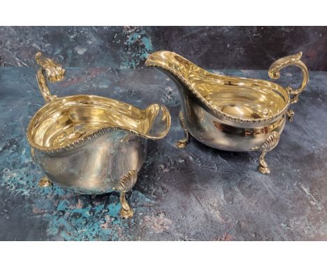 A pair of Edwardian silver sauce boats, beaded rim, c-scroll handle with leaf detail, raised on three pad feet, 17 cm long, J