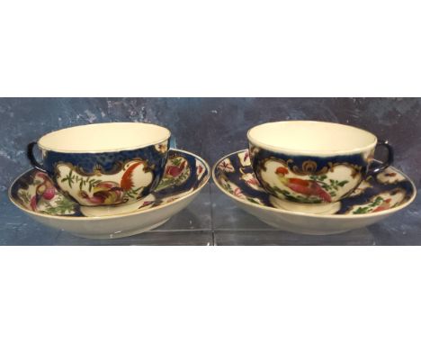 A pair of Worcester blue scale&nbsp; teacups and saucers, painted with alternating cartouche and vase shaped panels each with