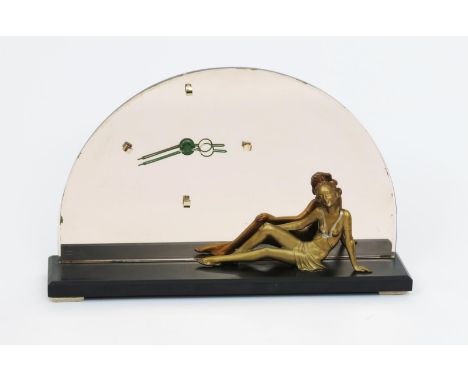 A patinated metal and peach mirror glass mantle clock,  domed glass back with offset dial, set with a resting female figure i