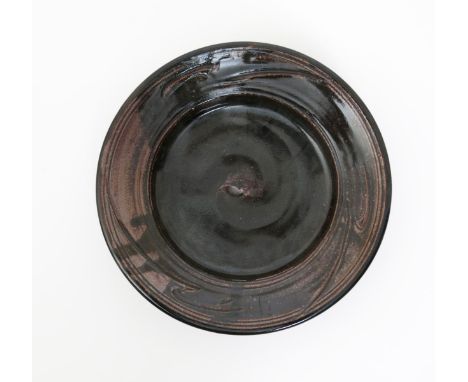 •Jim Malone (born 1946) a stoneware charger, incised with simple stroke design, covered in a tenmoku glaze, impressed seal ma