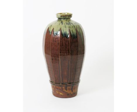 •Mike Dodd (born 1943) a tall stoneware vase, shouldered, faceted form covered in a running tenmoku glaze, the shoulder with 