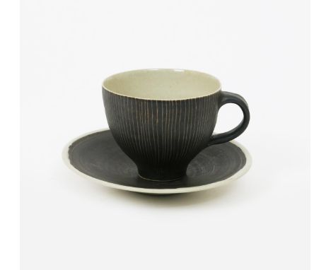 •Dame Lucie Rie D.B.E (1902-1995) a tea cup and saucer, decorated to the exterior with sgraffito lines in a manganese glaze o