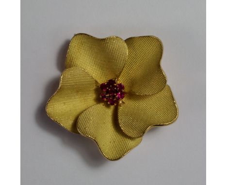 An 18ct gold and ruby flower head brooch, the petals with knurled finish and ruby set stamens, attached pendant loop to verso