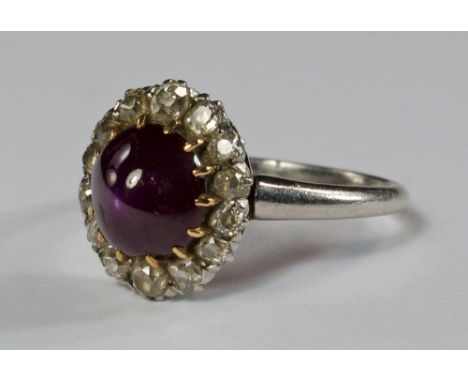 A cabochon ruby and diamond ring, the central domed cabochon ruby surrounded by old cut diamonds, set in unmarked white metal