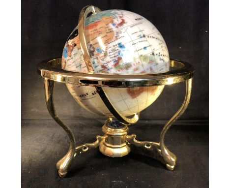 A table top globe, the countries of The World picked out in faux coloured stone and shell on a white ground, the brass finish