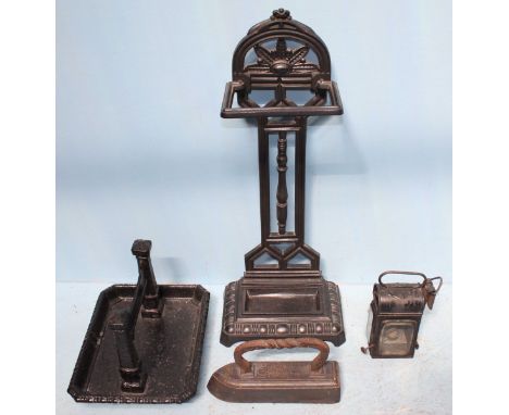 Four various iron items including a walking stick stand, a boot scrape, a clothes iron and a signal lamp.