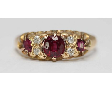 An 18ct gold ruby and diamond ring, the pierced mount, centrally claw set with a ruby and flanked by two smaller rubies and f
