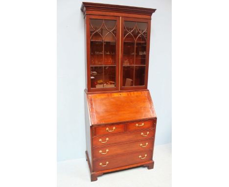 An early 20th century mahogany bureau bookcase, the shaped cornice with dentil moulding above two glazed doors enclosing two 