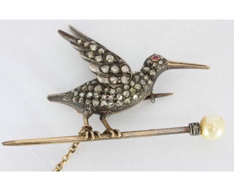 A gold & silver set bird brooch, set with rose cut diamonds and ruby eye, on a pearl topped pin.
