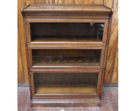 An oak Globe Wernicke style bookcase, with shaped cornice and three sections with up and over, glazed fronts, enclosing stora