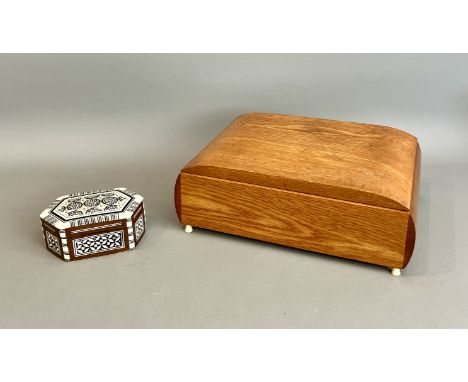 A mid-century honey oak musical jewellery box - the domed lid over convex sides, opening to reveal a blue velvet lined interi
