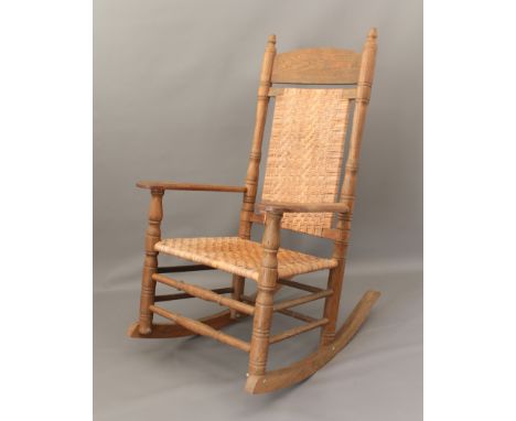 An American light oak rocking chair with herringbone caned seat and back - the left arm signed 'Brumby Chair Co. - Marietta'.