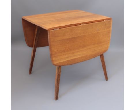 A 1970s beech and elm drop-flap dining table, probably Ercol - the slightly rounded rectangular top on square, tapering, spla